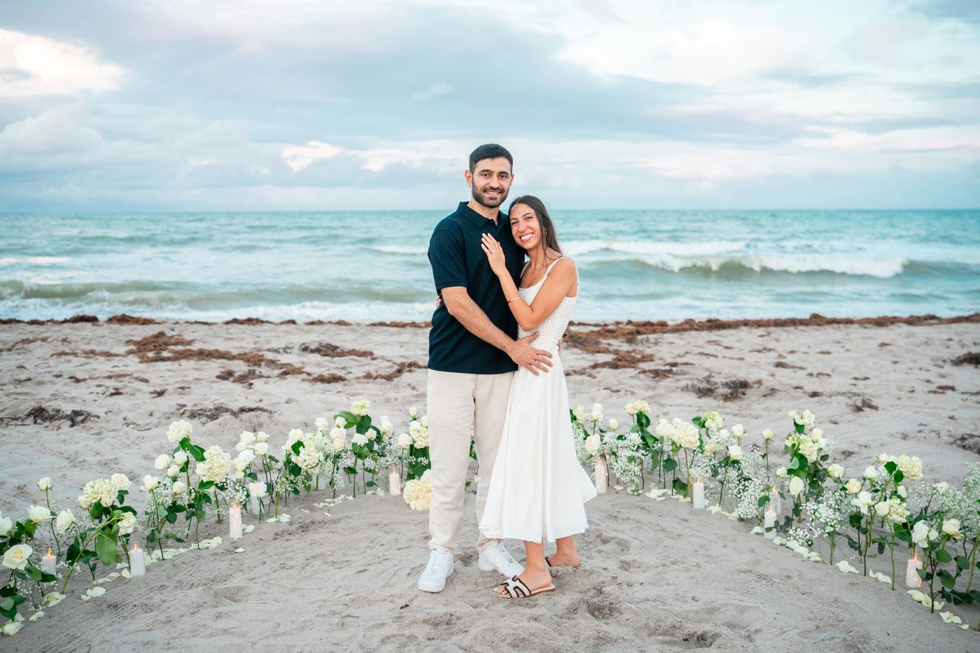 Talya and Sahar standing together on the beach surrounded by white flowers